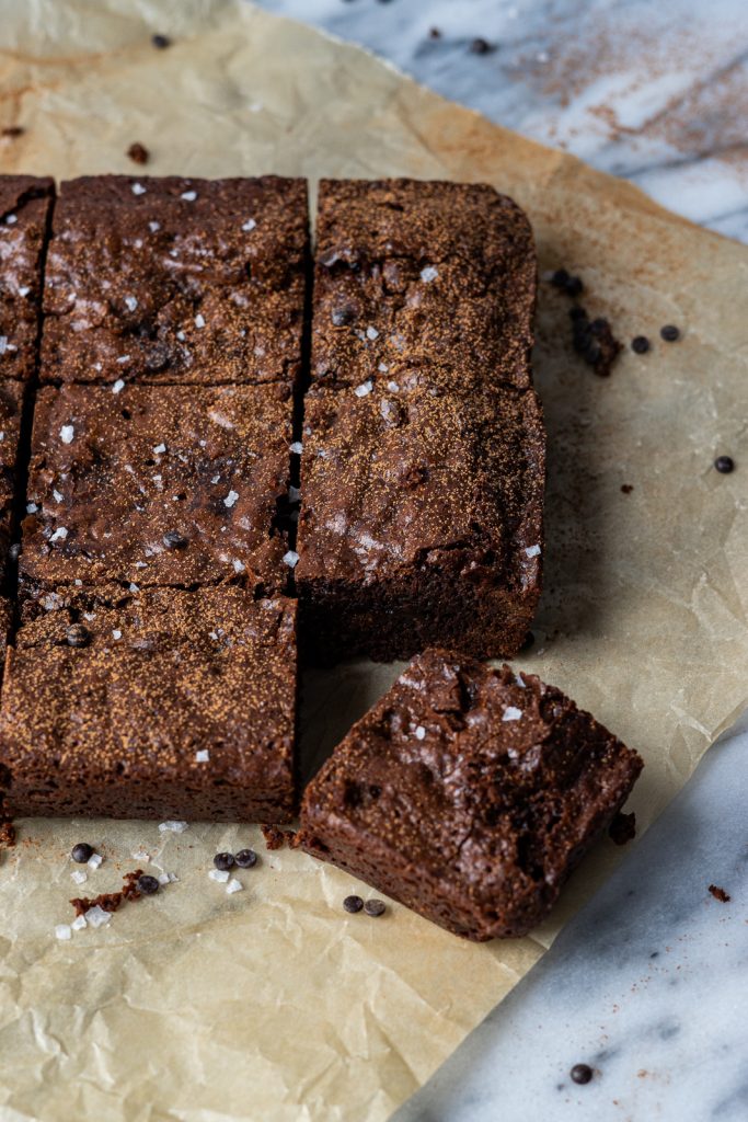 A close up of vegan brownies. Six brownies are visible with the corner brownie askew.