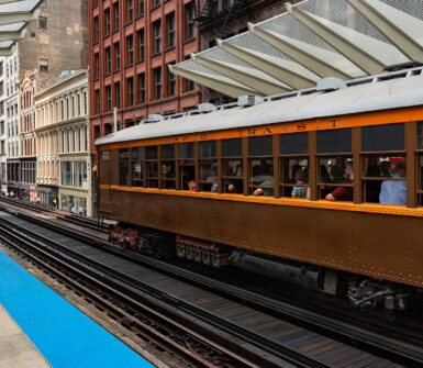 Train number 4272 of the 4000-Series is departing the Washington and Wabash train station in downtown Chicago. There are skyscrapers in the distance. This train is part of the CTA Heritage Fleet.