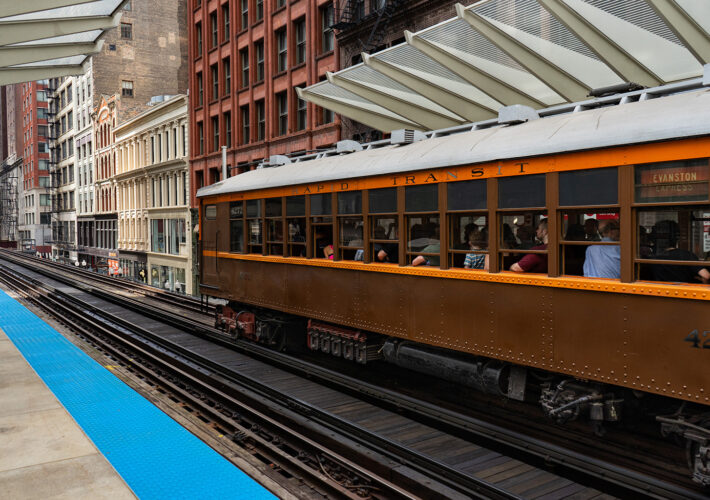 Train number 4272 of the 4000-Series is departing the Washington and Wabash train station in downtown Chicago. There are skyscrapers in the distance. This train is part of the CTA Heritage Fleet.